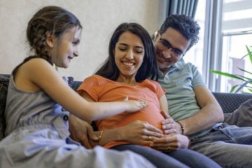 آموزش مسائل جنسی به کودکان ـ پدر، مادر و کودکی که با لمس شکم برآمده مادرش کنجکاوی خود را نشان می‌دهد