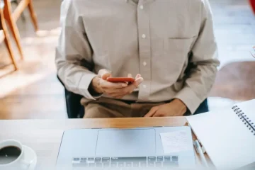کار مرد با موبایل جلوی لپتاپ
